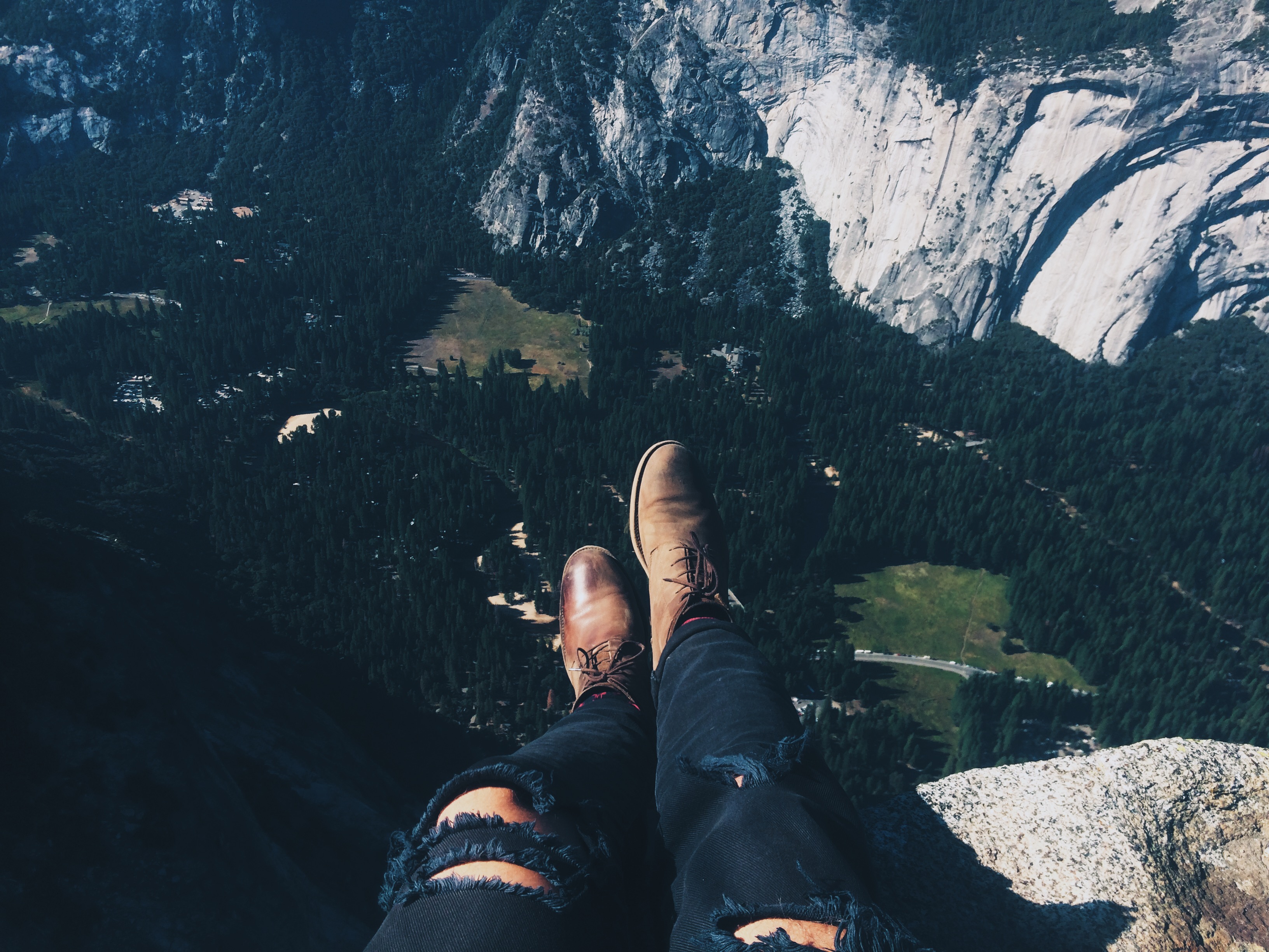 torn jeans and boots sitting on cliff